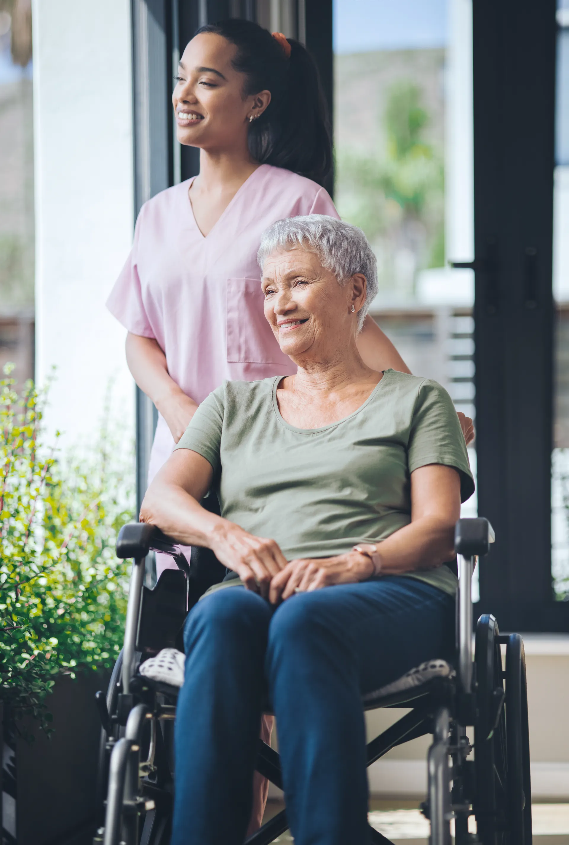 Auxiliaire accompagnant une personne âgée en fauteuil